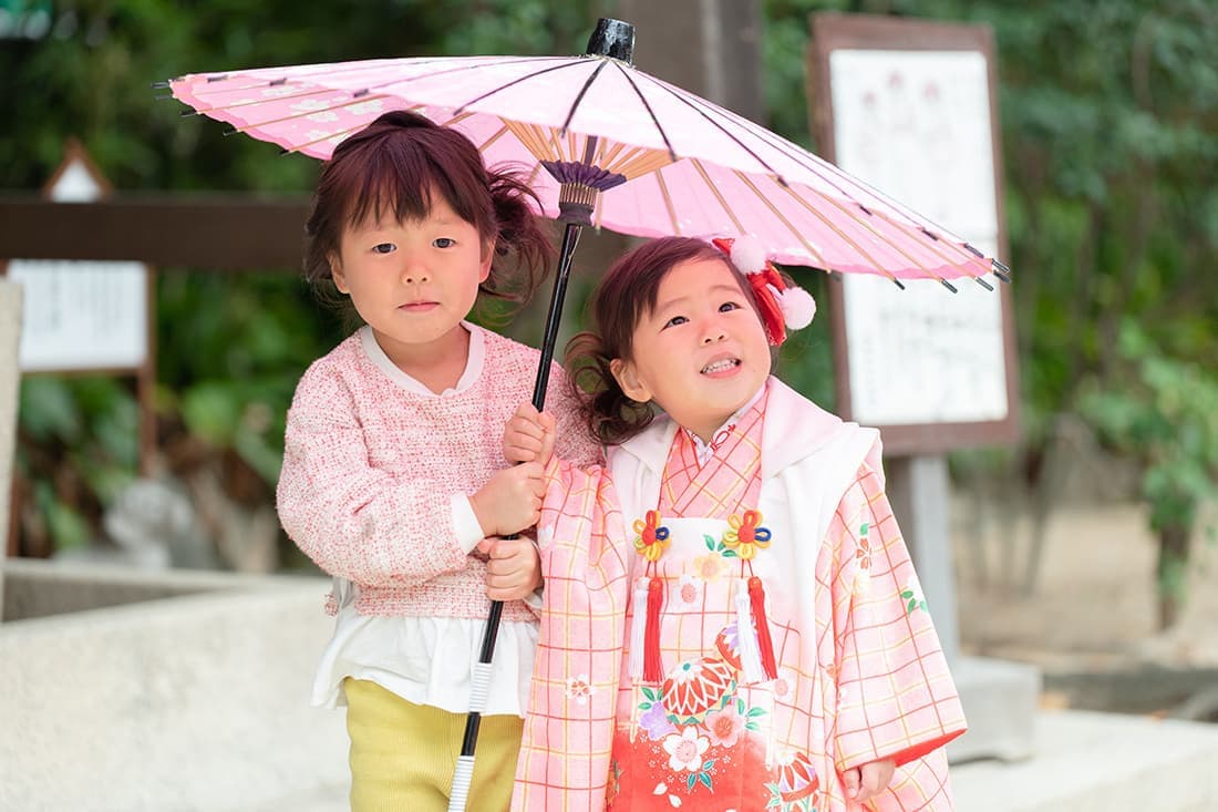 七五三の出張撮影｜ピンク色の和傘に入った姉妹。とっても嬉しそうです。